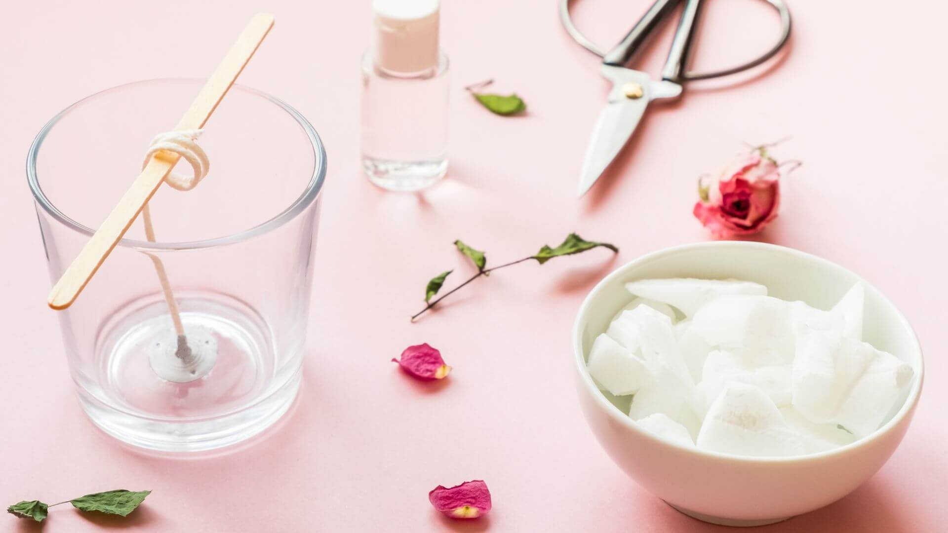 wax, wick, dry roses: ingredients for making handmade candle on a pink background